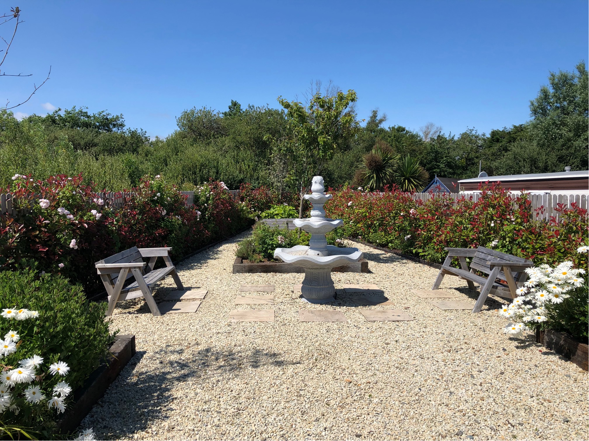 Peace garden at Central Holiday Park Rosslare, with a fountain, benches and flowering plants